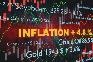 Die Schrift Inflation sticht orange hervor im Hintergrund sieht man Aktienkurse