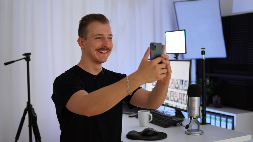 Ricardo Tunnissen hält in seinem Studio hält sein Handy in der Hand und lacht ins Handy