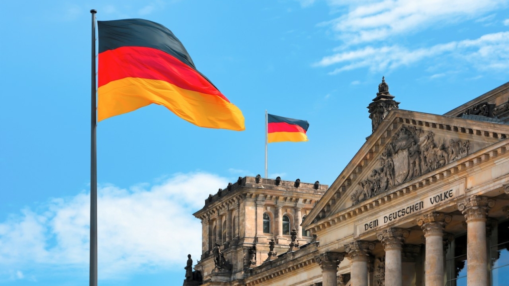 Deutschland-Fahne vor der Kuppel des Reichstags in Berlin