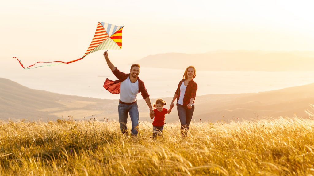 Happy family father, mother and child daughter launch a kite on nature at sunset