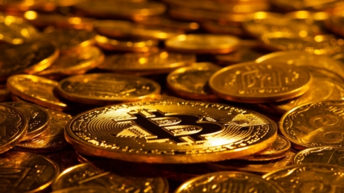 Gold Kryptowährung Bitcoin vor dem Hintergrund vieler anderer Goldmünzen in hartem Licht. Neues Konzept des steigenden Wertes der digitalen Kryptowährungen der Blockchain-Branche. Nahaufnahme.