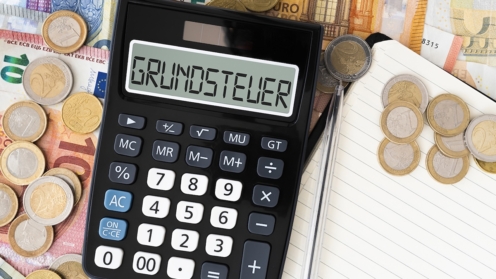 Grundsteuer Grundsteuer oder Grundsteuer im Taschenrechner mit Euro-Scheinen und Münzen im Hintergrund