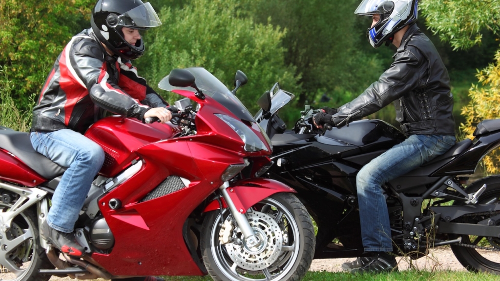 zwei Motorradfahrer stehen auf Landstraße, Seitenansicht